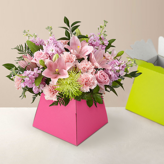 Pink trapezoid flower box holding a bouquet of lilies and roses