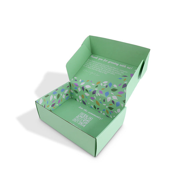 Green art paper mailer box, open with colorful leaf-pattern insert inside.