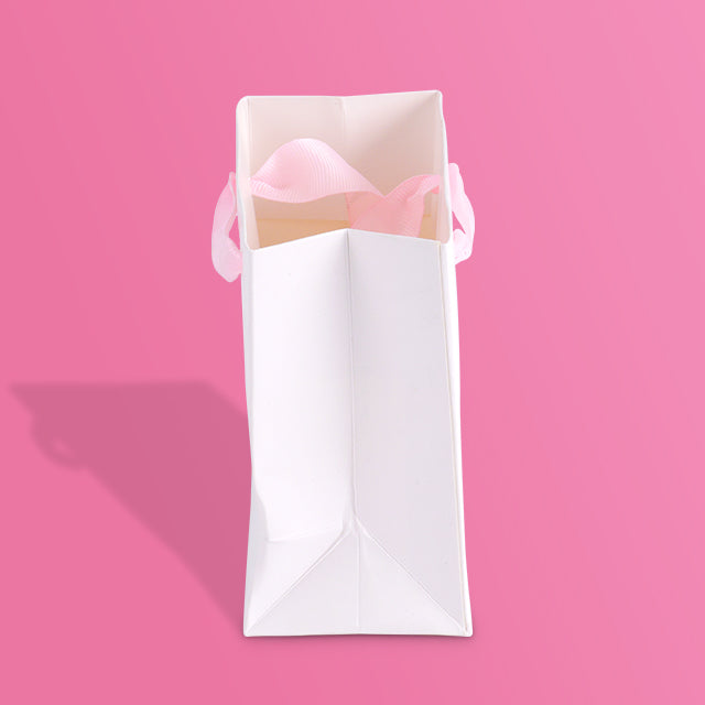 White paper tote bag standing with pink ribbon and PICADILI logo