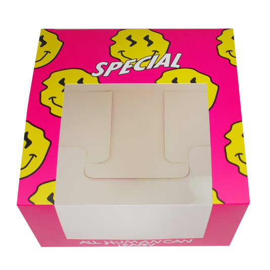 Pink cardboard food box with yellow smiley pattern and front window with handle cutouts