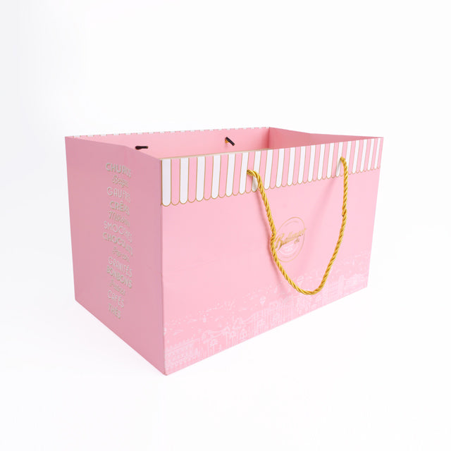 Pink rigid carrier bag with striped top, yellow rope handles, and side text detail.