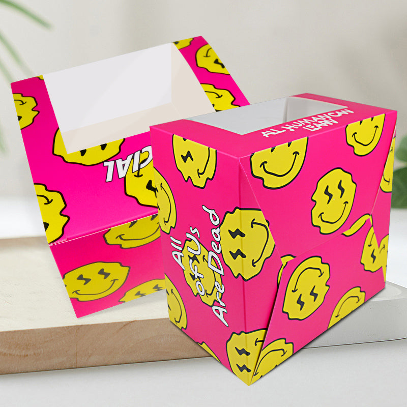 Pink cardboard food box with yellow smiley pattern, open top, and side text