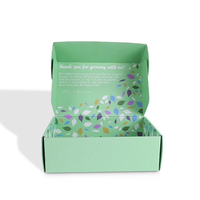 Green art paper mailer box, open with colorful leaf-pattern bottom and greeting text.