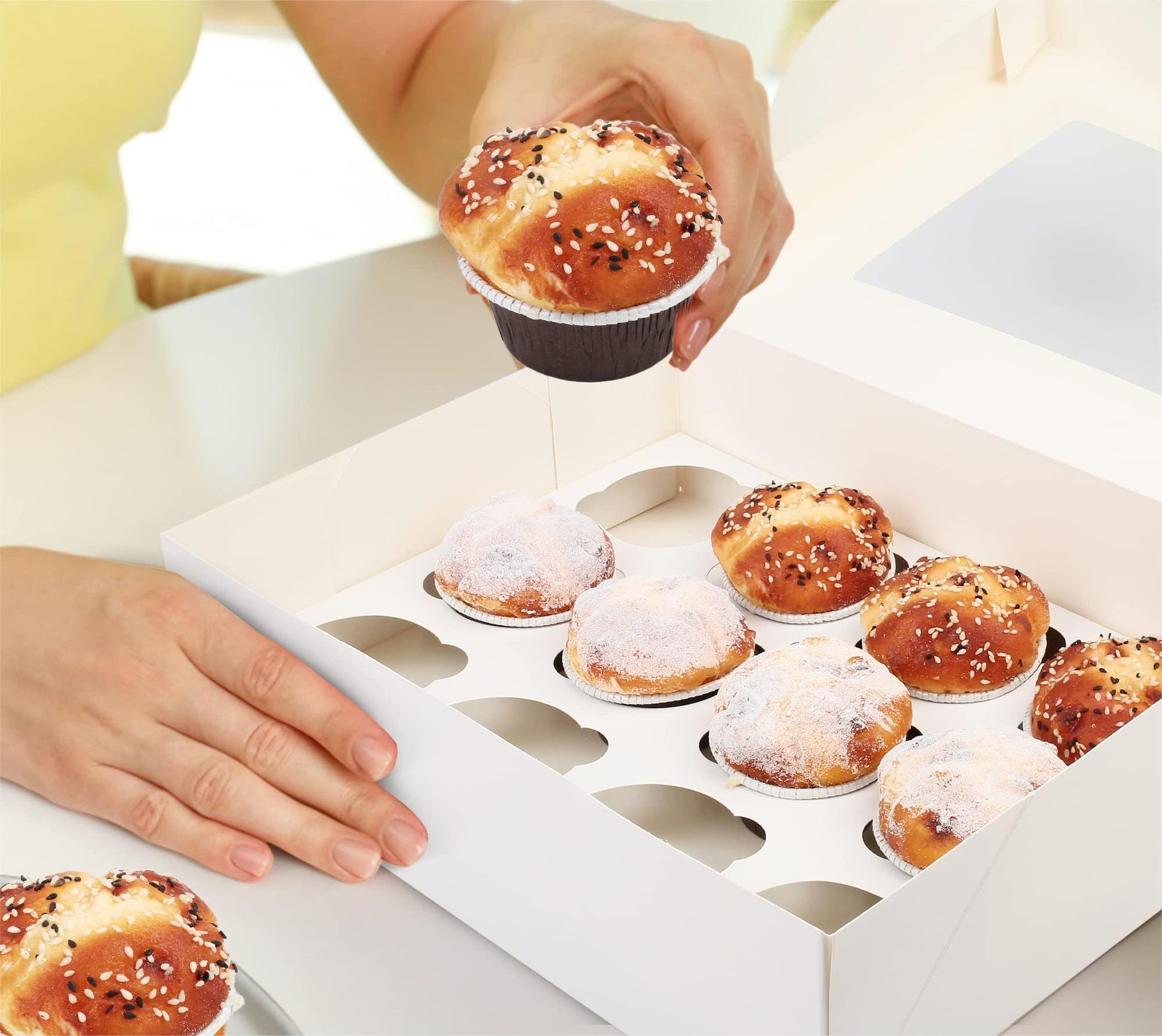 White bakery box with window, hands placing cupcakes into cutout tray