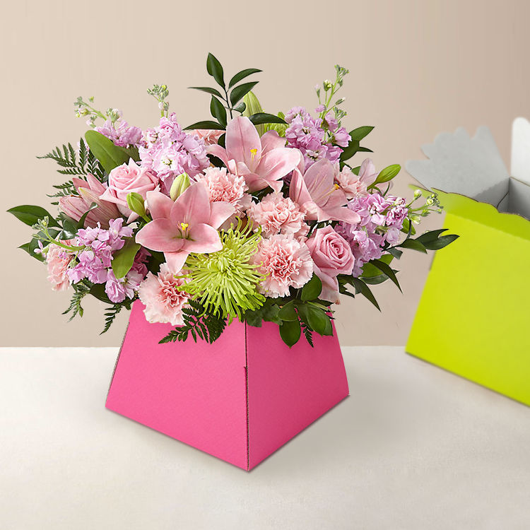 Pink trapezoid flower box holding a bouquet of lilies and roses