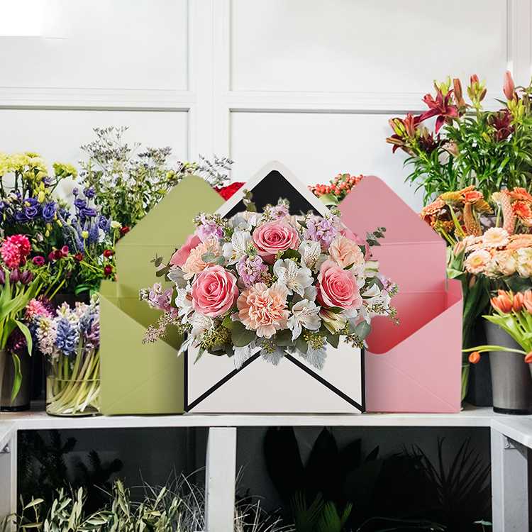 Envelope style floral gift boxes in green, white, and pink with fresh flowers inside