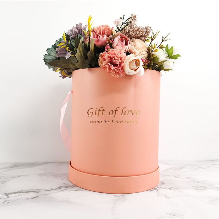 Round cardboard flower gift box with ribbon handle and gold foil "Gift of love" text