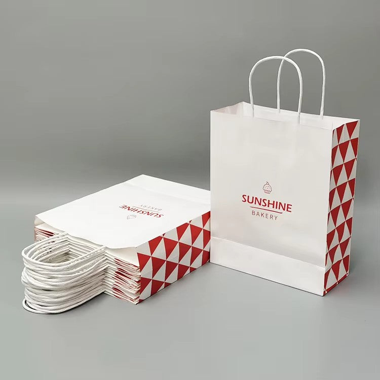 Stack of custom white paper bags with red geometric triangle print and twisted handles