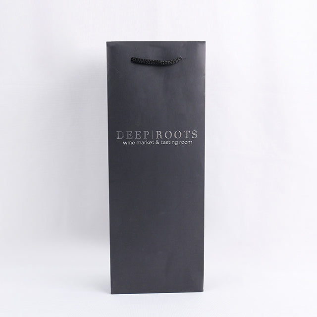 Black paper wine gift bag with top rope handle and 'DEEP ROOTS' logo on front