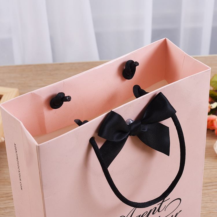 Open pink shopping bag showing interior and satin ribbon bow handle attachment
