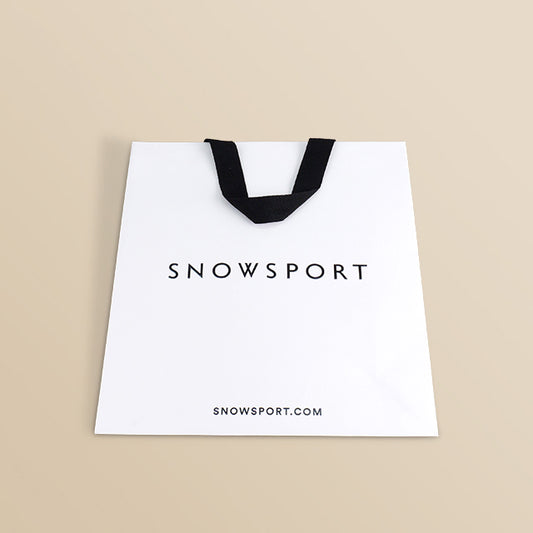 White paper shopping bag with black ribbon handles and SNOWSPORT logo