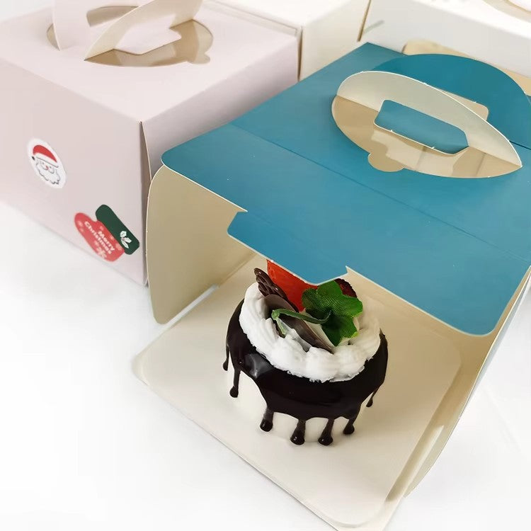 Opened blue and white cake box with decorated slice inside, handle visible