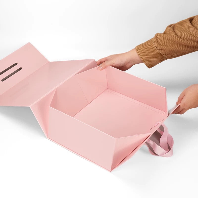 Pink foldable gift box with ribbon handle, open showing empty interior