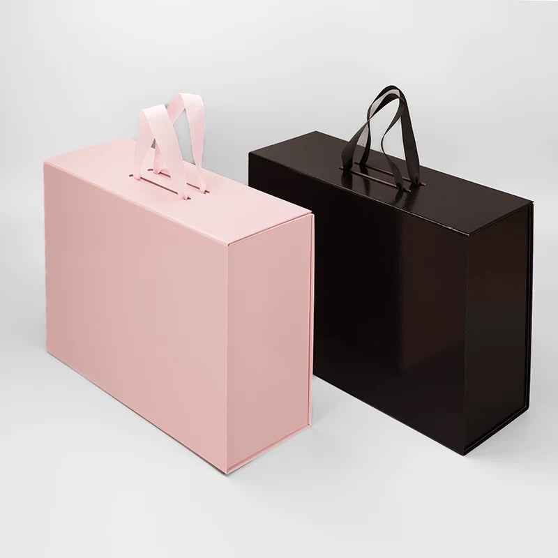 Pink and black foldable gift boxes with ribbon handles, shown side by side