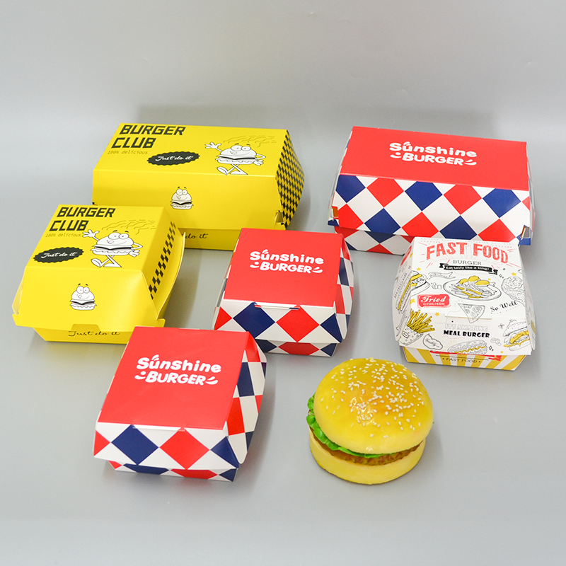 Assorted printed burger boxes with fries tray and burger, colorful packaging