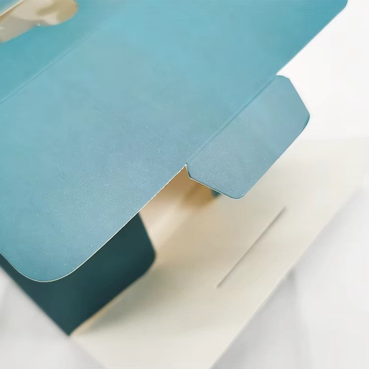 Close-up of blue cake box lid with handle cutout and open tray